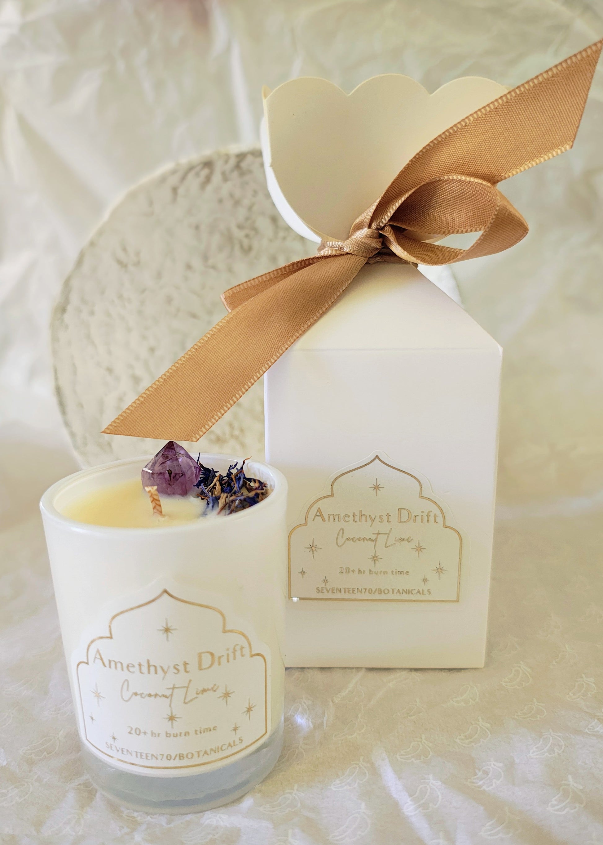 Candle with bon bon packaging featuring a gold bow on a light background